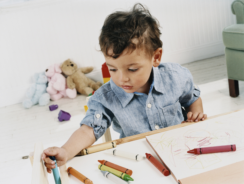 Young child coloring with crayons